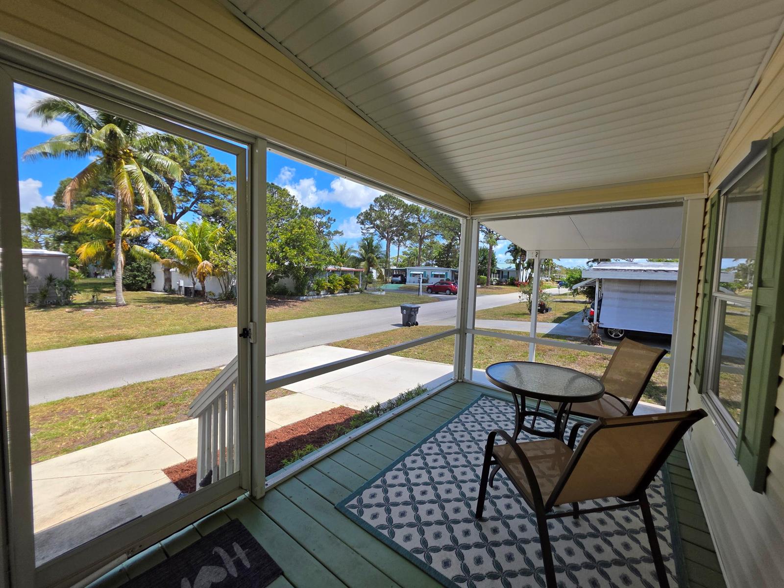 A screened-in porch features a small glass table, two chairs, and a patterned rug — 4218 6th Court, Lantana FL 33462, LANTANA, FL