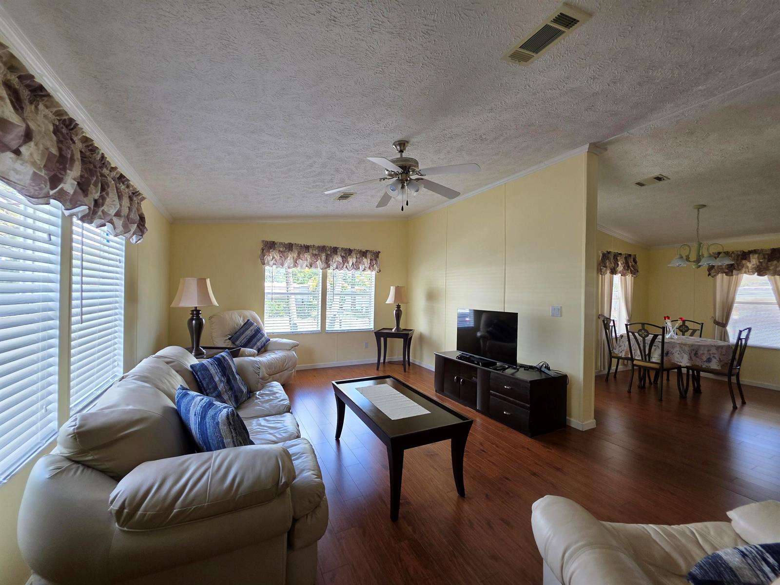 A living room with light yellow walls, wood flooring, and a dining area beyond — 4218 6th Court, Lantana FL 33462, LANTANA, FL