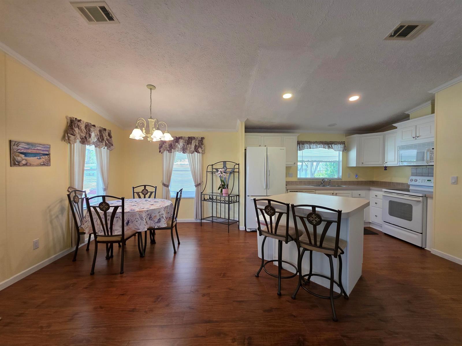A kitchen and dining area featuring light yellow walls, white cabinetry, and wood-look flooring — 4218 6th Court, Lantana FL 33462, LANTANA, FL
