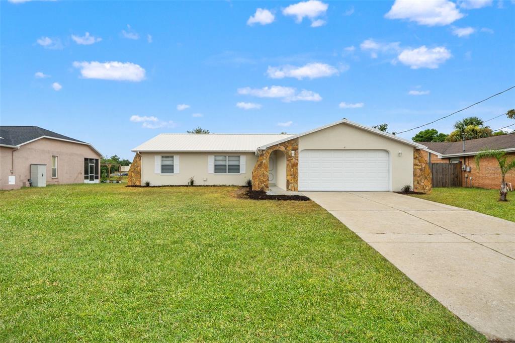 A single-story house with a stone-accented entryway, white garage door, and a concrete driveway — 5510 ALDERWOOD STREET, SPRING HILL, FL