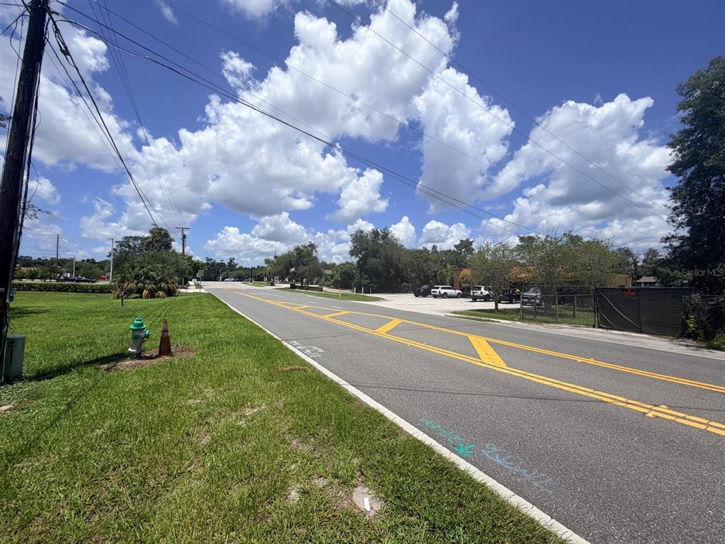 A paved road with yellow lane markings runs past a grassy area and a parking lot — 1329 LAKE DRIVE, CASSELBERRY, FL