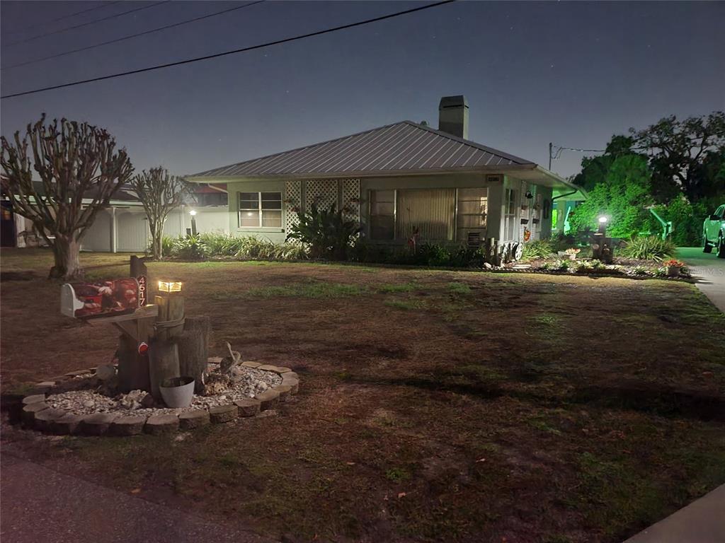 A single-story house with a metal roof and a landscaped front yard at night — 4517 8TH STREET COURT E, ELLENTON, FL