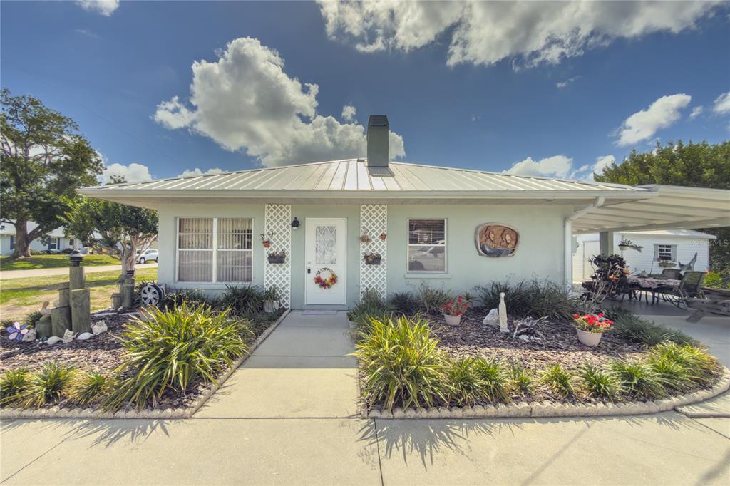 A light green single-story house with a metal roof and a front garden — 4517 8TH STREET COURT E, ELLENTON, FL