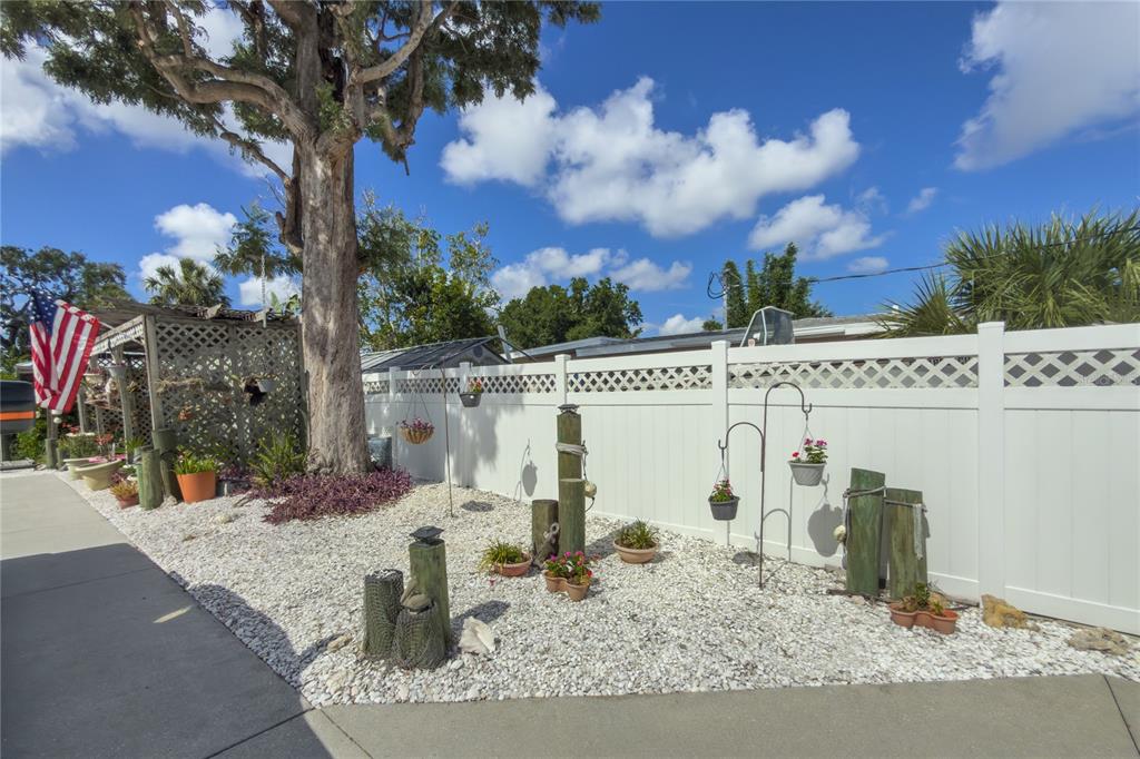 A white vinyl fence borders a gravel yard with potted plants and wooden posts — 4517 8TH STREET COURT E, ELLENTON, FL