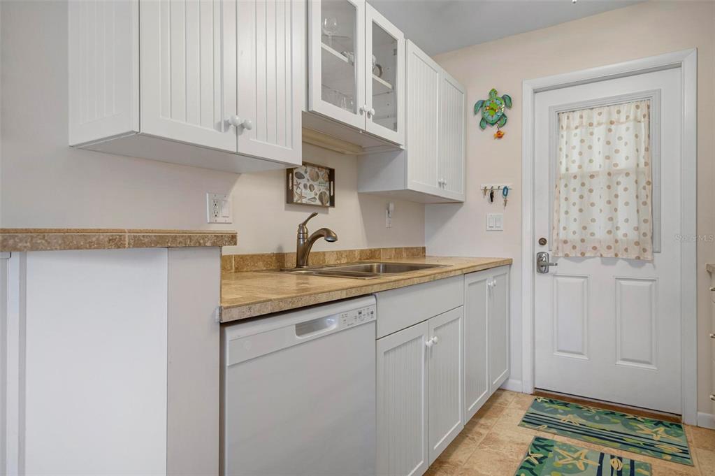 A kitchen features white beadboard cabinets, a tan tiled countertop, and a white dishwasher — 3808 GULF OF MEXICO DRIVE UNIT E205, LONGBOAT KEY, FL