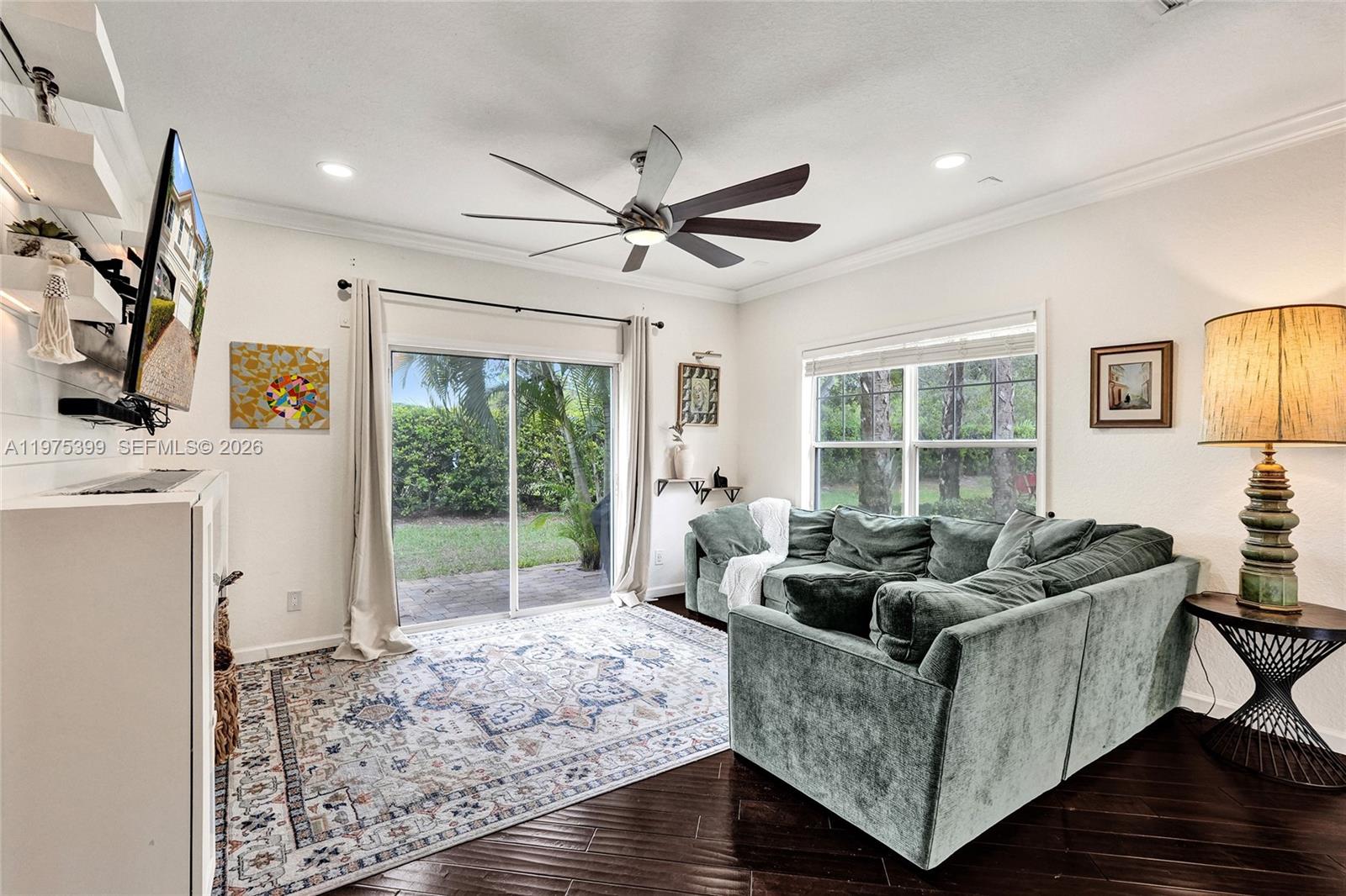 A living room features a green sectional sofa, a patterned rug, and a ceiling fan — 4501 Windmill Palm Way, Green Acres FL 33463, GREEN ACRES, FL