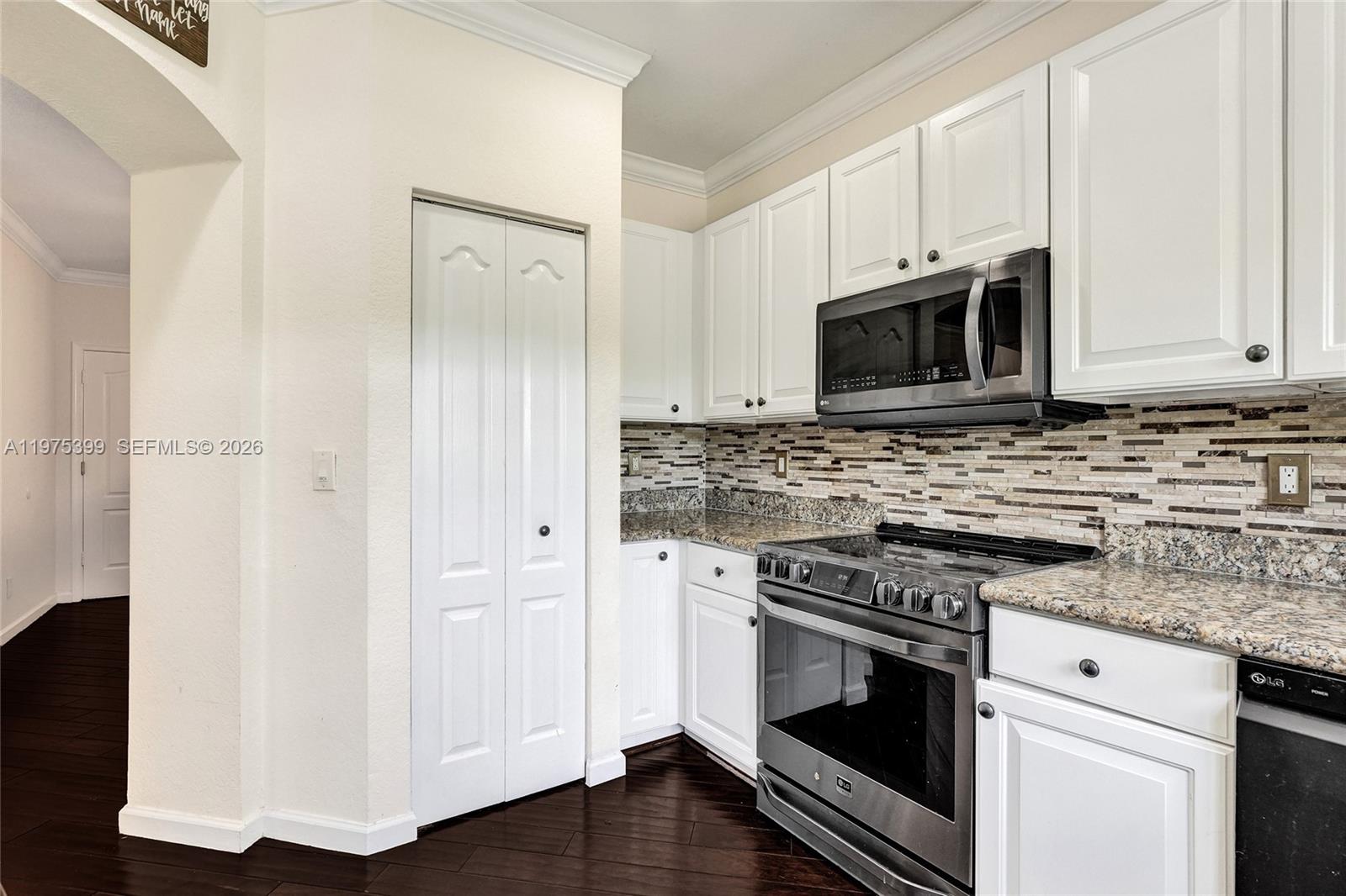 A kitchen features white cabinets, granite countertops, stainless steel appliances, and a tiled backsplash — 4501 Windmill Palm Way, Green Acres FL 33463, GREEN ACRES, FL