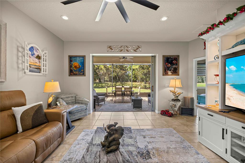 A living room with tile flooring, a leather sofa, and sliding doors opening to a patio — 7684 SW 94TH CIRCLE, OCALA, FL