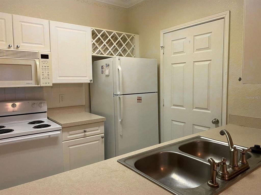 A kitchen features white cabinets, a white stove, a microwave, and a white refrigerator — 1216 S MISSOURI AVENUE UNIT 428, CLEARWATER, FL