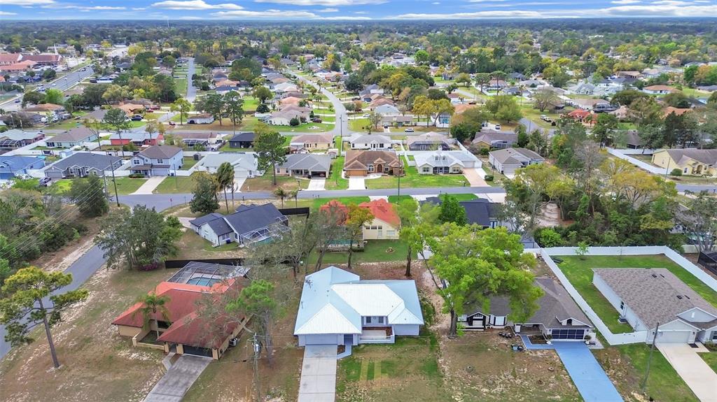 An aerial view shows a suburban neighborhood with single-family homes, paved streets, and mature trees — 10452 FORDHAM STREET, SPRING HILL, FL