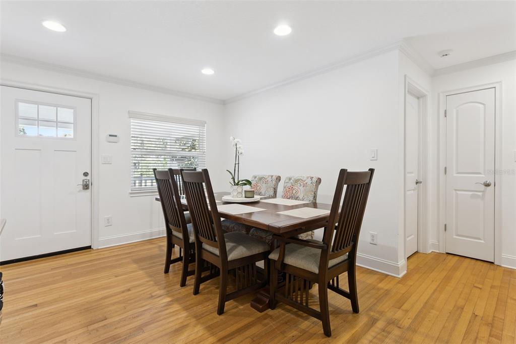 A dining room with a wooden table, six chairs, hardwood floors, and a white door — 309 NIBLICK WAY, ORLANDO, FL