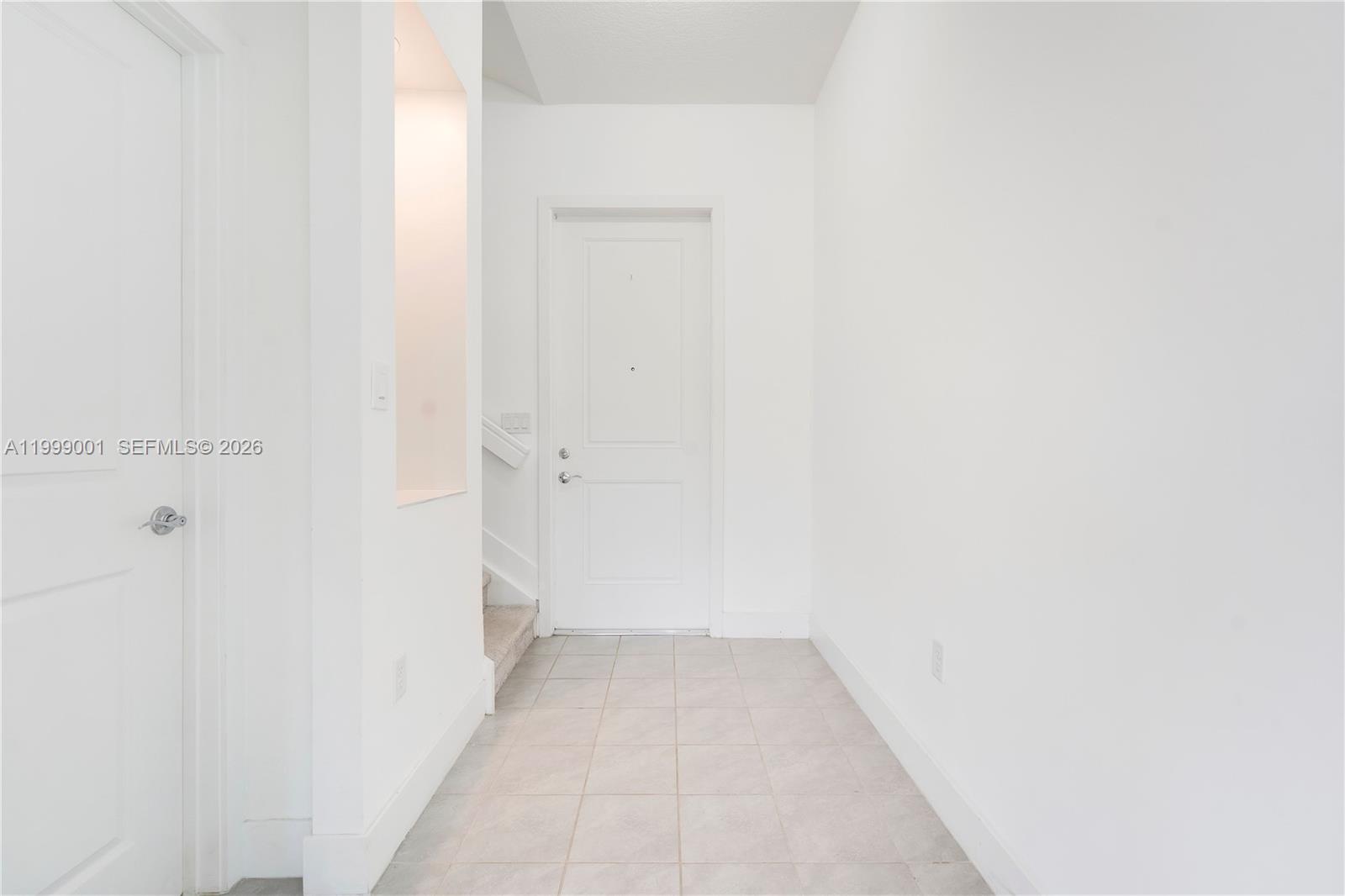A white entryway features tiled flooring, a front door, and a staircase to the left — 5546 Agostino Way, Ave Maria FL 34142, AVE MARIA, FL