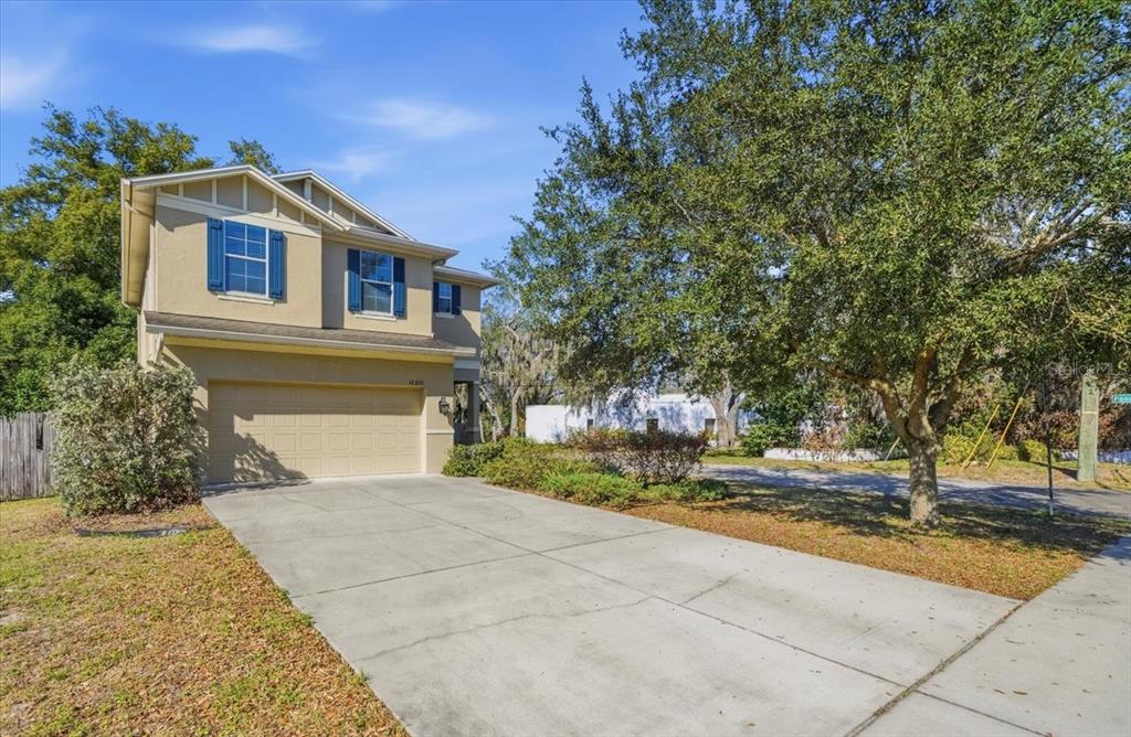A two-story house with a beige exterior, blue shutters, and a concrete driveway — 12330 N ROME AVENUE, TAMPA, FL