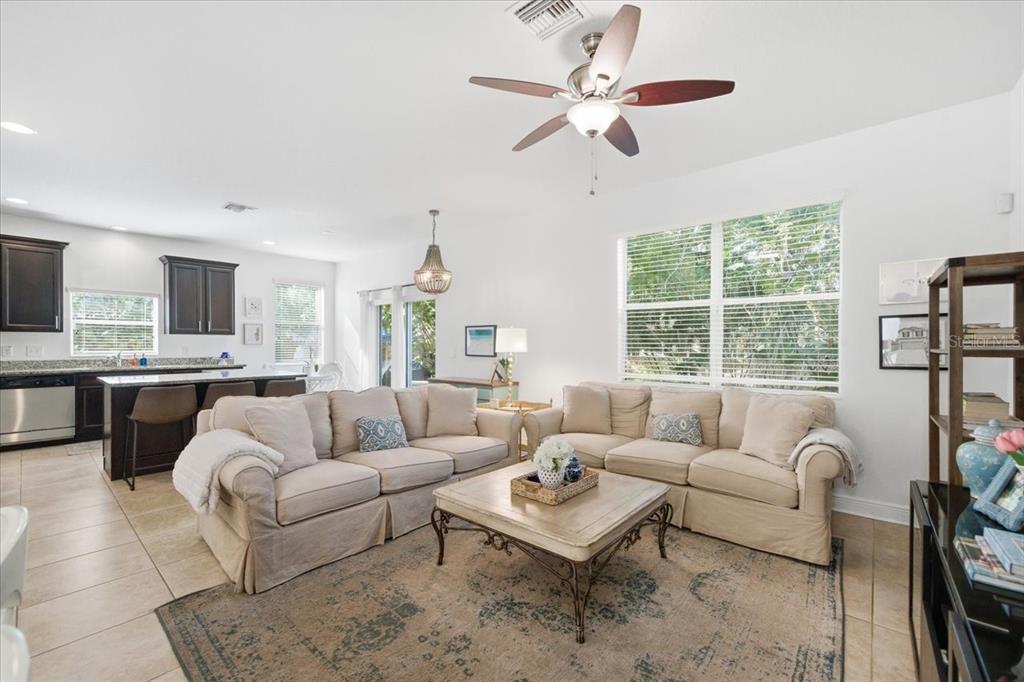 A living room with beige sofas, a coffee table, and an open kitchen with dark cabinets — 12330 N ROME AVENUE, TAMPA, FL