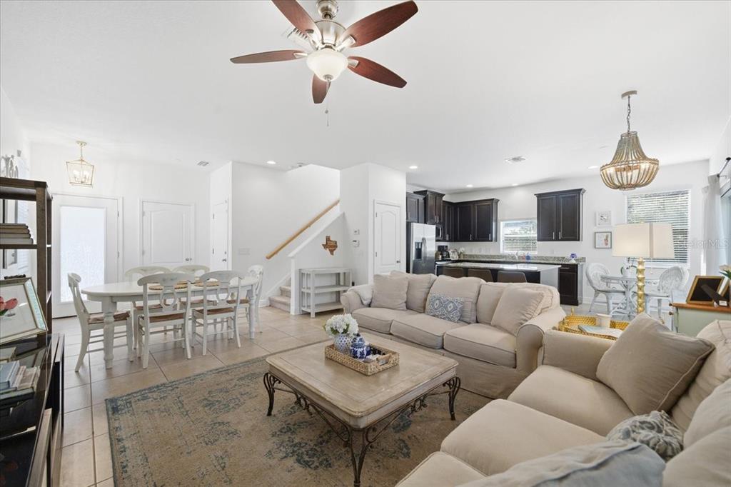 An open-concept living room and kitchen featuring tile floors, neutral furniture, and a ceiling fan — 12330 N ROME AVENUE, TAMPA, FL