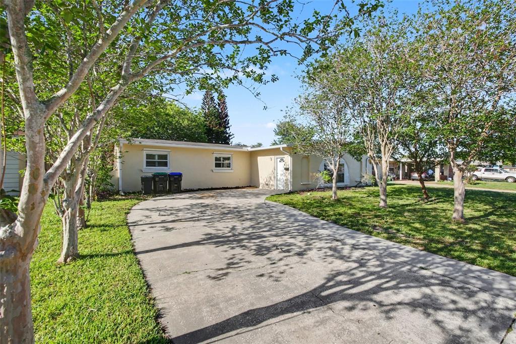 A single-story house with a concrete driveway, light-colored exterior, and several trees in the yard — 722 GALSWORTHY AVENUE, ORLANDO, FL