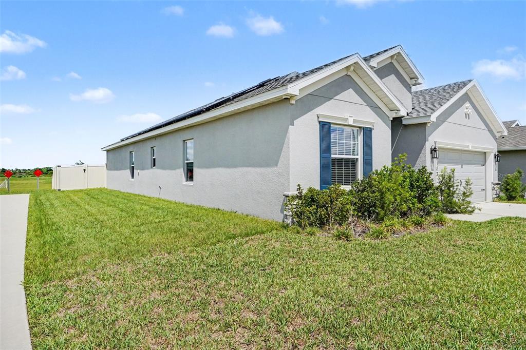 The exterior side and front of a single-story house with a garage and lawn — 6103 HAMMOCK ISLAND WAY, HAINES CITY, FL
