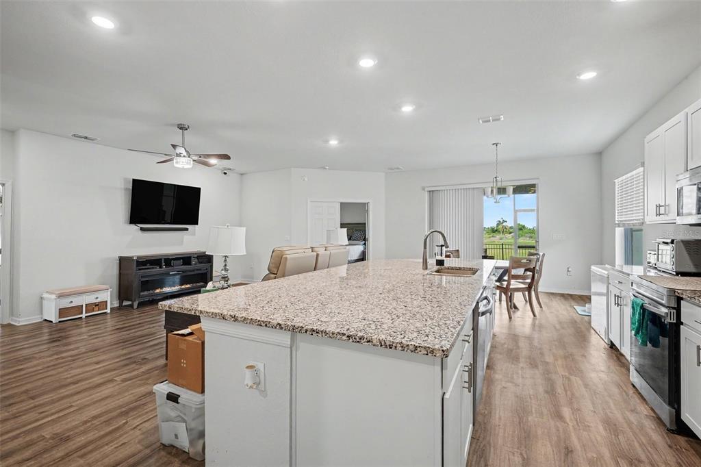 A kitchen with a granite island and stainless steel appliances overlooks a living area — 6103 HAMMOCK ISLAND WAY, HAINES CITY, FL