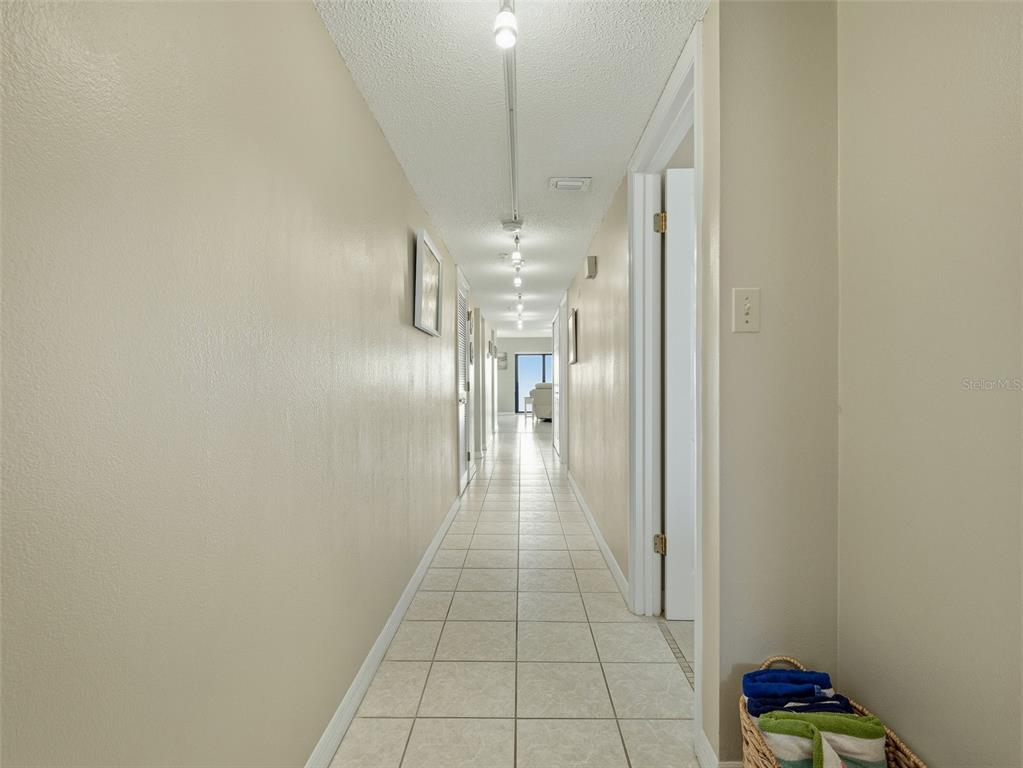 A long hallway with beige walls, white tile flooring, and recessed ceiling lighting — 5207 S ATLANTIC AVENUE UNIT 426, NEW SMYRNA BEACH, FL