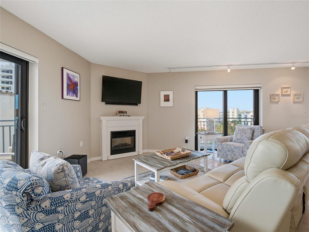 A living room features a fireplace, a television, two sliding glass doors, and seating furniture — 5207 S ATLANTIC AVENUE UNIT 426, NEW SMYRNA BEACH, FL