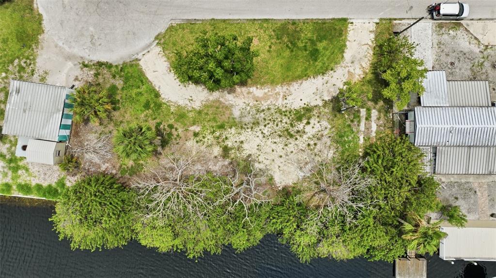 An aerial view shows a vacant waterfront lot situated between two small houses — 13039 PORT COURT, HUDSON, FL