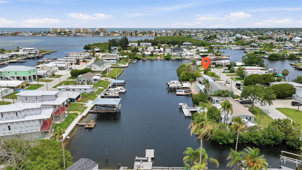 An aerial view shows waterfront homes along a canal with boat docks and palm trees — 13039 PORT COURT, HUDSON, FL