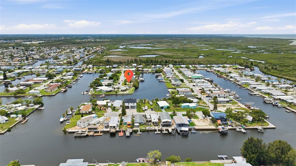 An aerial view shows waterfront homes and boat docks along a canal in a coastal community — 13039 PORT COURT, HUDSON, FL