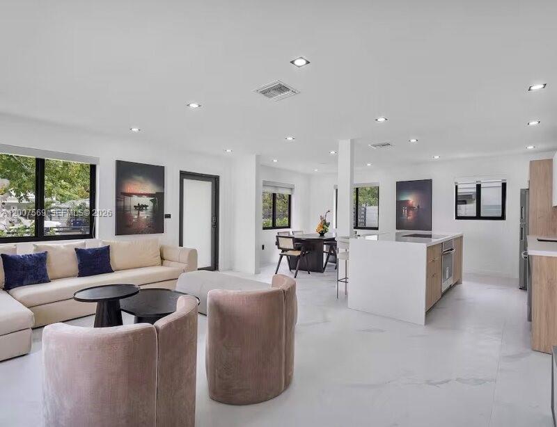 An open-concept living and kitchen area features white walls, tile flooring, and modern furnishings — 400 NW 40th St, Miami FL 33127, MIAMI, FL