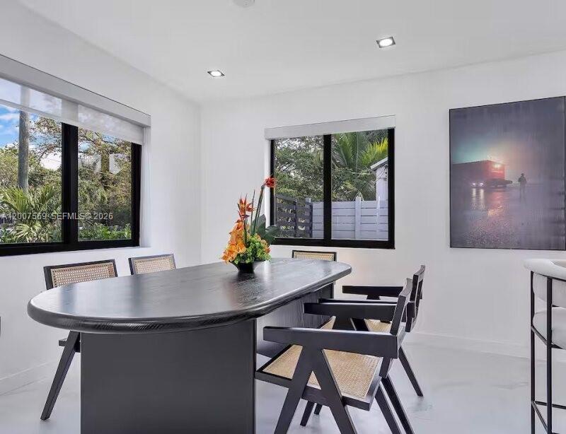 A modern dining room features a dark oval table, cane-back chairs, and large windows — 400 NW 40th St, Miami FL 33127, MIAMI, FL