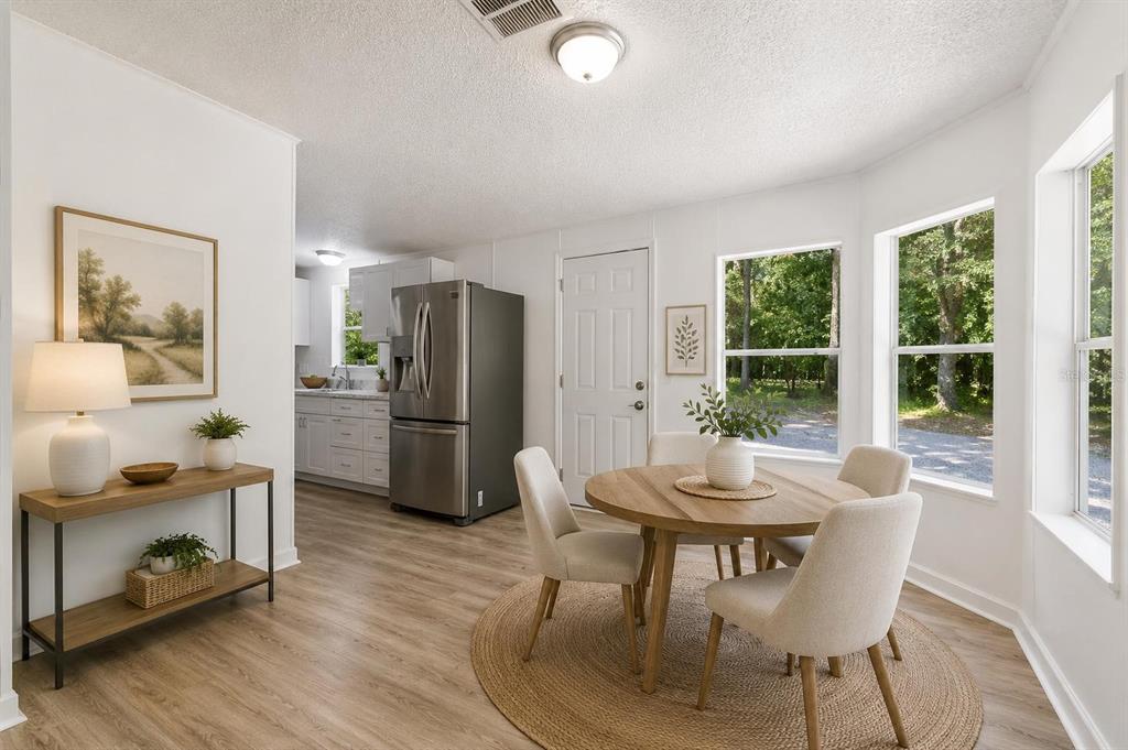 A bright dining area features a round wooden table, four chairs, and a nearby kitchen — 16475 BUDOWSKI ROAD, BROOKSVILLE, FL