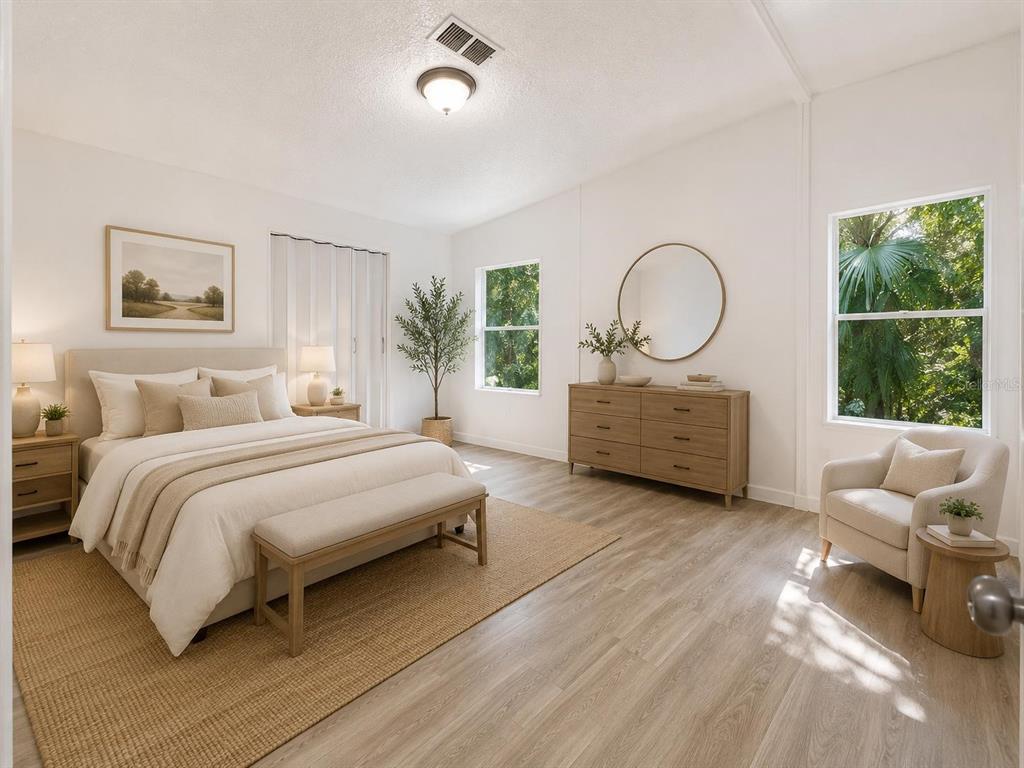 A bright bedroom features light wood flooring, a bed with a bench, and a dresser — 16475 BUDOWSKI ROAD, BROOKSVILLE, FL