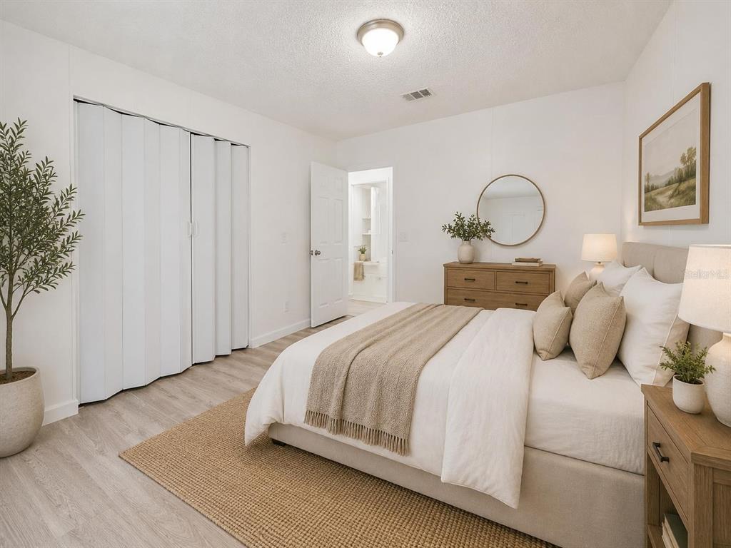 A bright bedroom features a bed with neutral bedding, a wooden dresser, and a closet — 16475 BUDOWSKI ROAD, BROOKSVILLE, FL