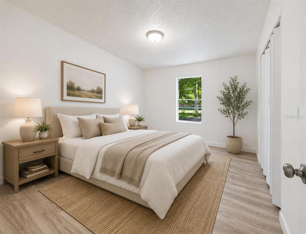 A bedroom features a queen bed, two nightstands, a window, and light wood-look flooring — 16475 BUDOWSKI ROAD, BROOKSVILLE, FL