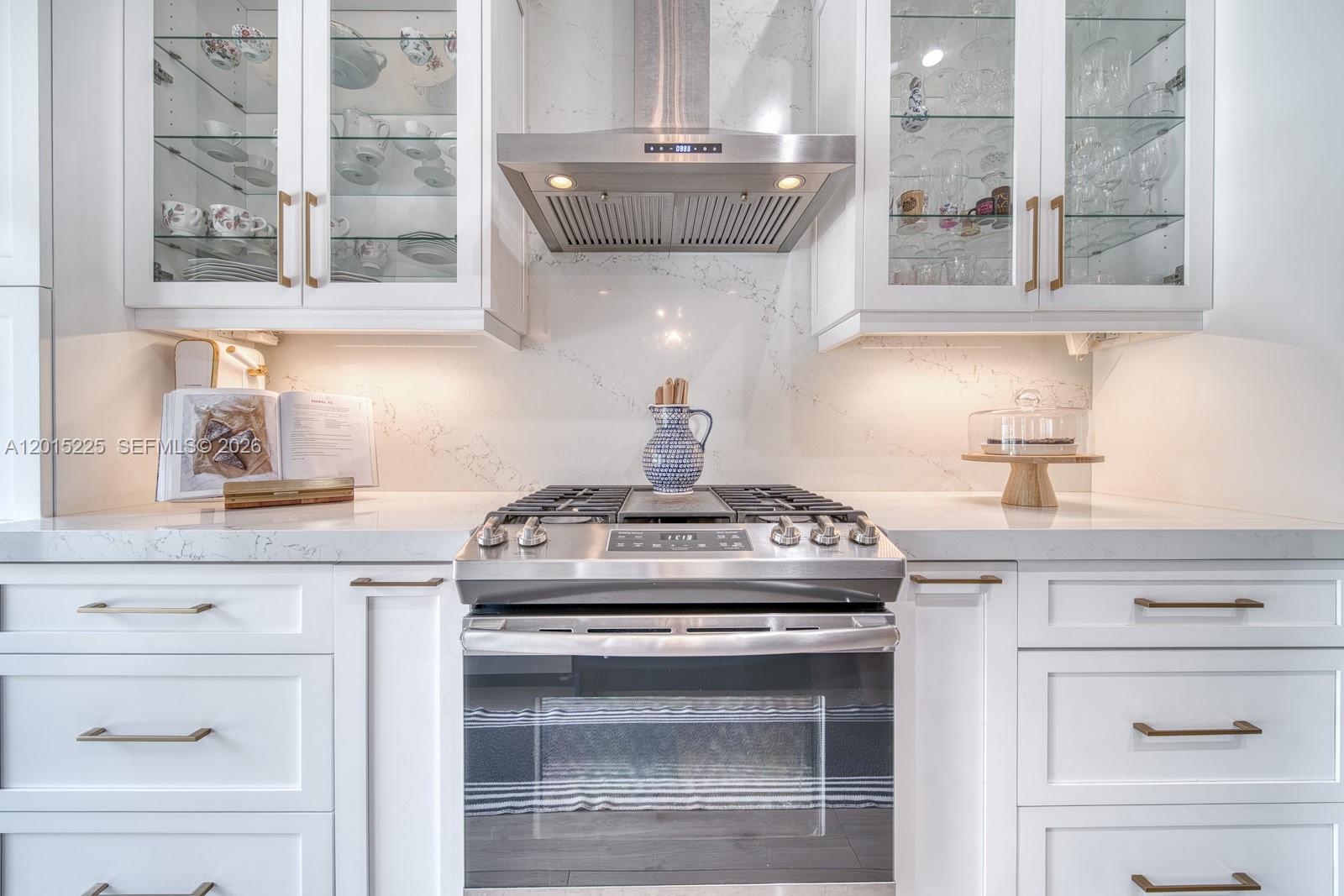 A kitchen features white cabinets, a stainless steel range, and a marble-patterned backsplash — 77 Gables Blvd, Weston FL 33326, WESTON, FL