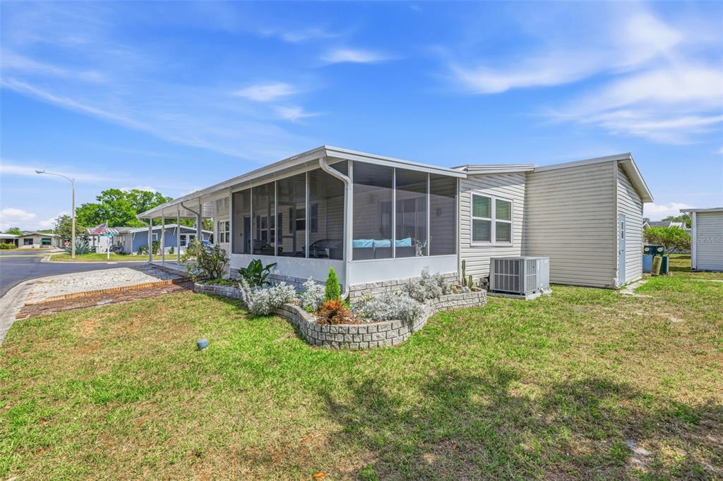 A single-story manufactured home with a screened-in porch and a stone-bordered garden bed — 3125 SHORT LEAF STREET, WESLEY CHAPEL, FL