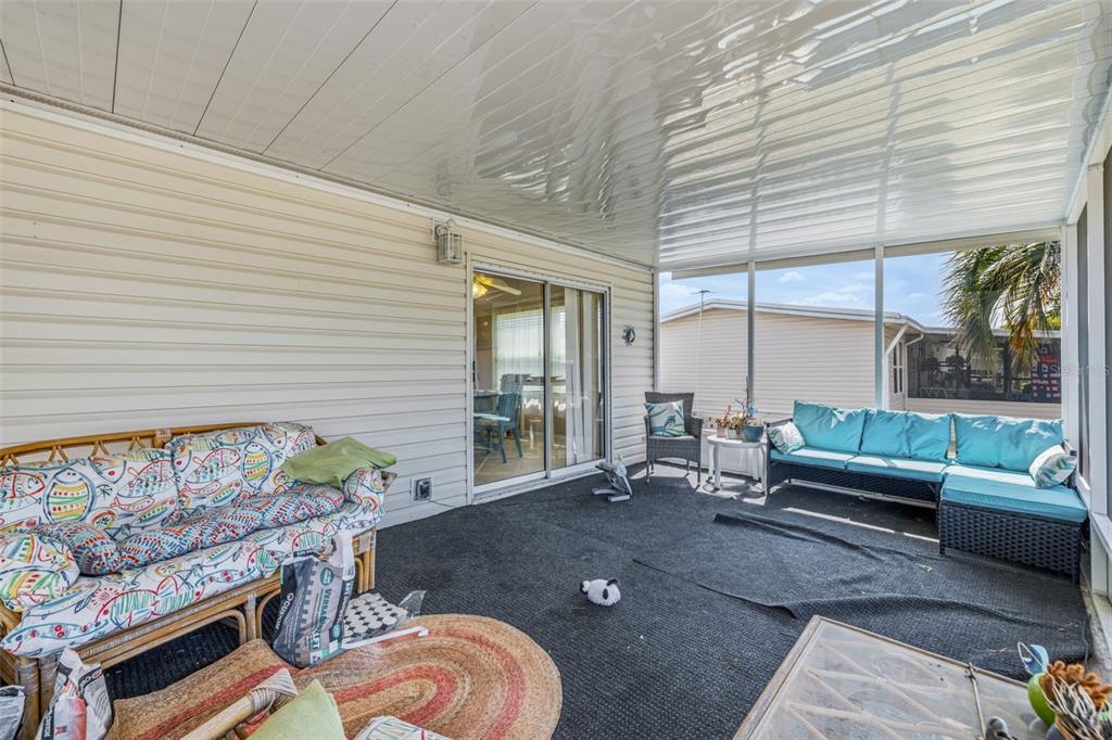 A screened-in porch features a patterned sofa, a blue sectional, and a dark carpet — 3125 SHORT LEAF STREET, WESLEY CHAPEL, FL