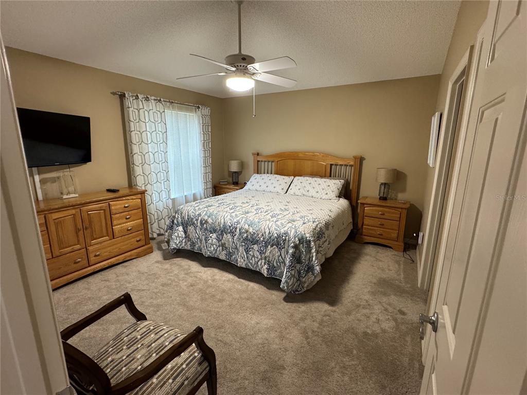 A bedroom features a wooden bed frame, matching nightstands, a dresser, and a ceiling fan — 1631 EDISTO LANE, THE VILLAGES, FL