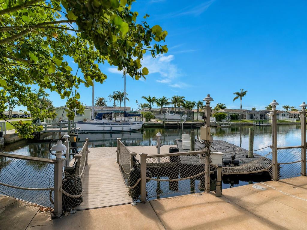 A wooden dock with a net railing leads to a floating dock on a canal — 5016 MARLIN DRIVE, NEW PORT RICHEY, FL