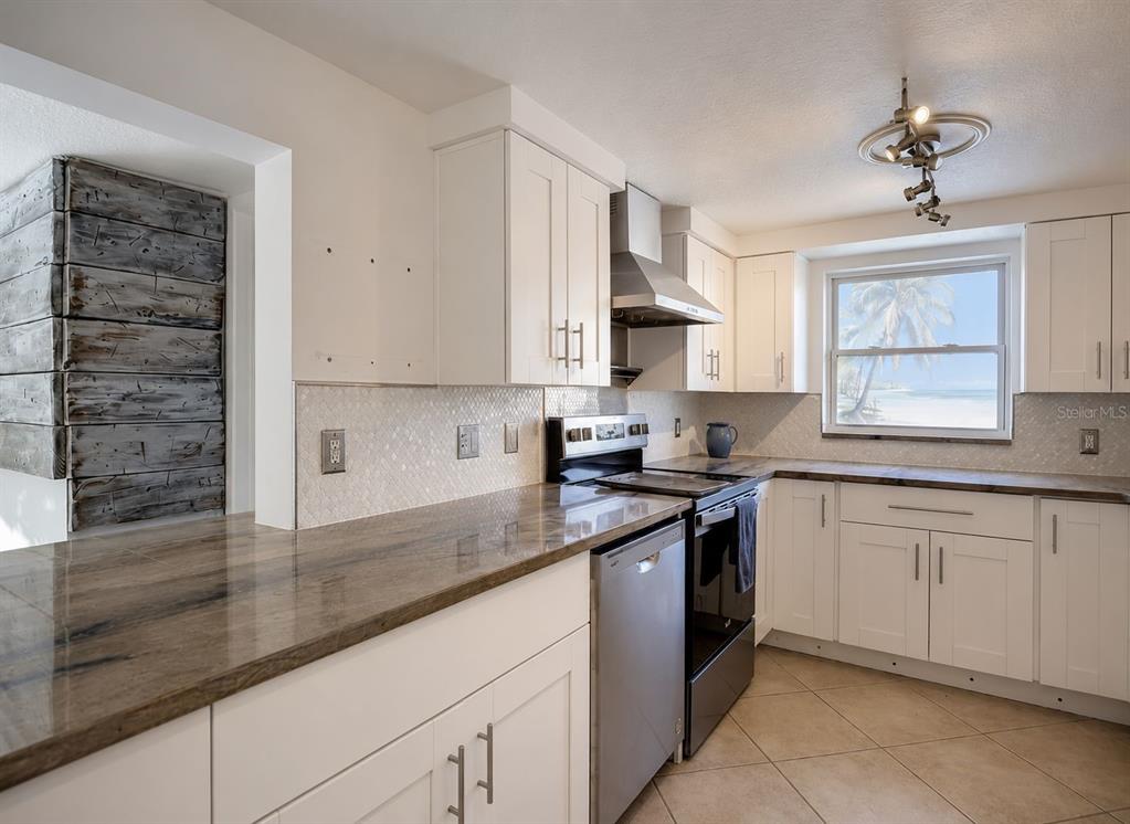 A kitchen with white cabinets, dark countertops, stainless steel appliances, and a view of the beach — 5016 MARLIN DRIVE, NEW PORT RICHEY, FL