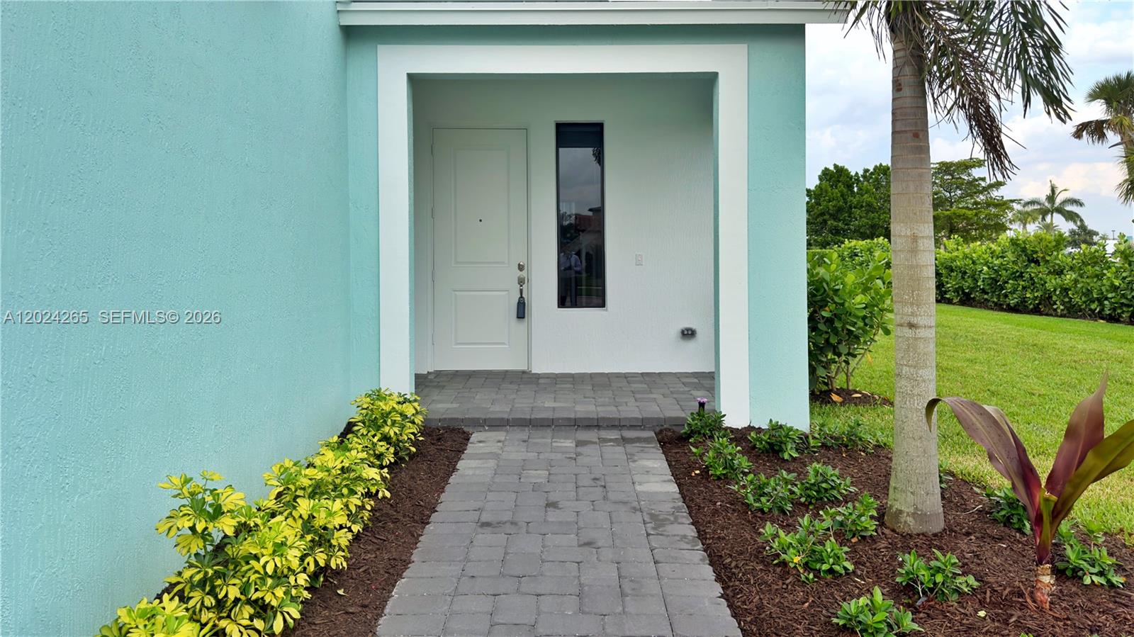 A paved walkway leads to the front entrance of a house with light blue exterior walls — 5021 Coquina Pl # 5021, Westlake FL 33470, WESTLAKE, FL
