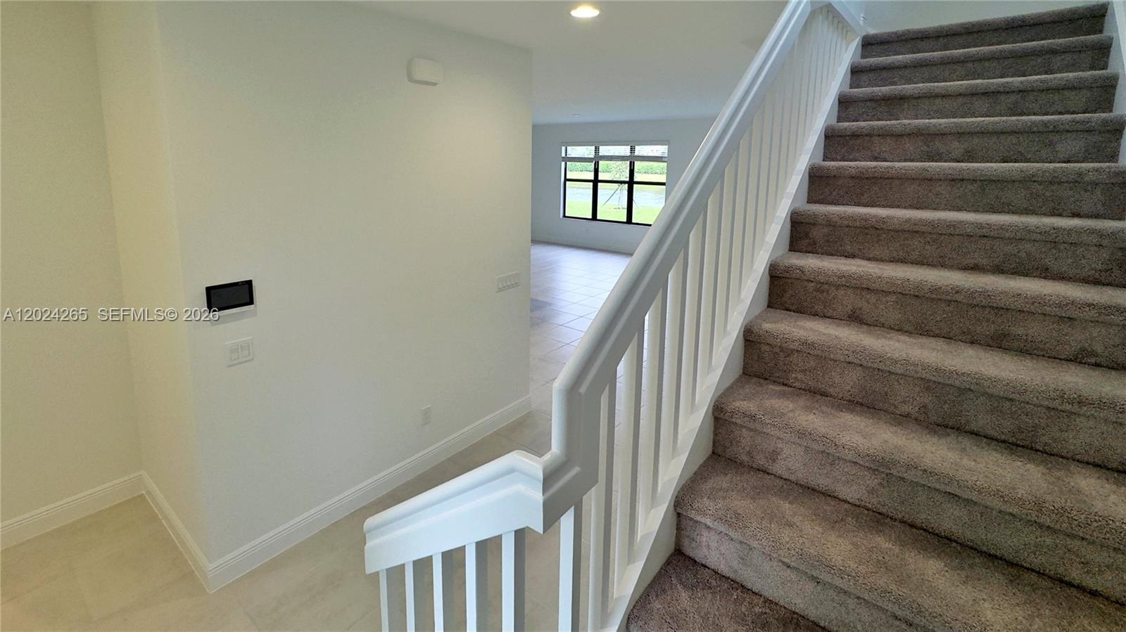 A carpeted staircase with a white railing leads down to a tiled living area — 5021 Coquina Pl # 5021, Westlake FL 33470, WESTLAKE, FL