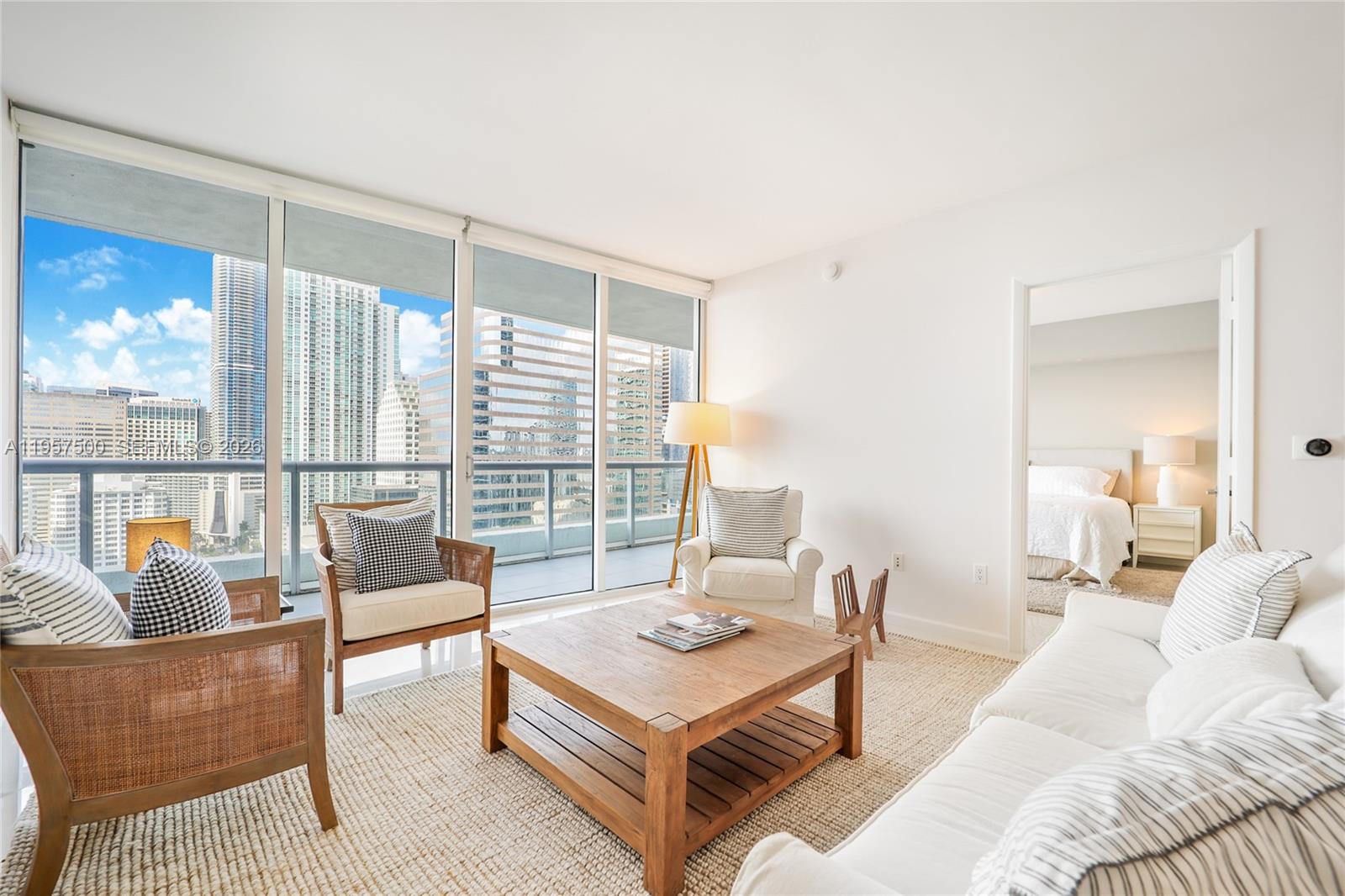 A bright living room features a wooden coffee table, white seating, and floor-to-ceiling windows — 495 Brickell Ave # 2303, Miami FL 33131, MIAMI, FL