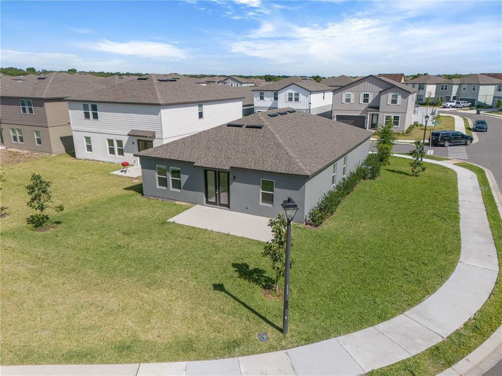 An aerial view shows the gray exterior of a single-story house with a concrete patio — 2375 LANCASHIRE STREET, DAVENPORT, FL