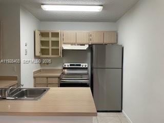 A kitchen features light wood cabinets, stainless steel appliances, and a laminate countertop — 18324 NW 68 # H, Hialeah FL 33015, HIALEAH, FL