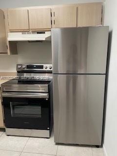 A kitchen features light wood cabinets, a stainless steel refrigerator, and a matching electric range — 18324 NW 68 # H, Hialeah FL 33015, HIALEAH, FL
