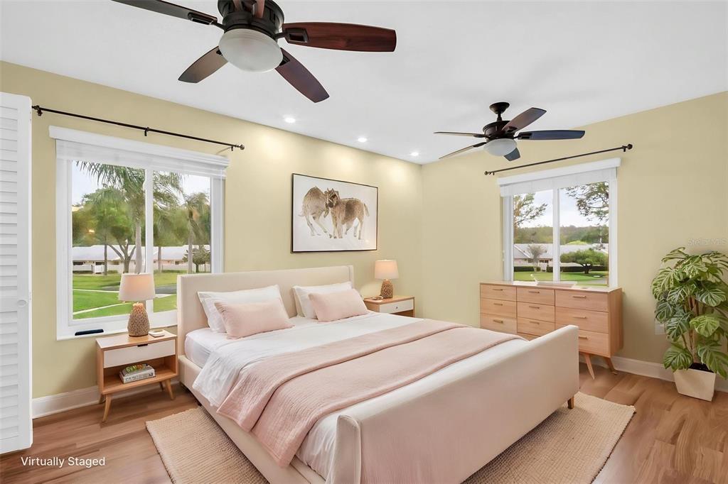 A bedroom with two ceiling fans, light-colored walls, wood flooring, and a queen-sized bed — 1400 PINE GLEN LANE UNIT D2, TARPON SPRINGS, FL