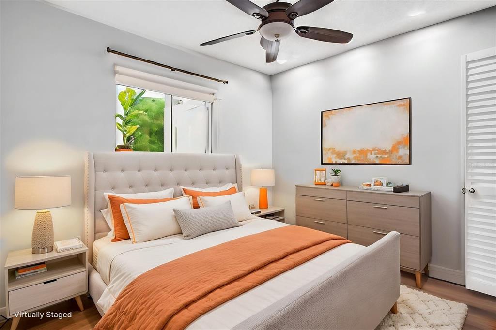 A bedroom features a tufted headboard, orange bedding, a dresser, and a ceiling fan — 1400 PINE GLEN LANE UNIT D2, TARPON SPRINGS, FL