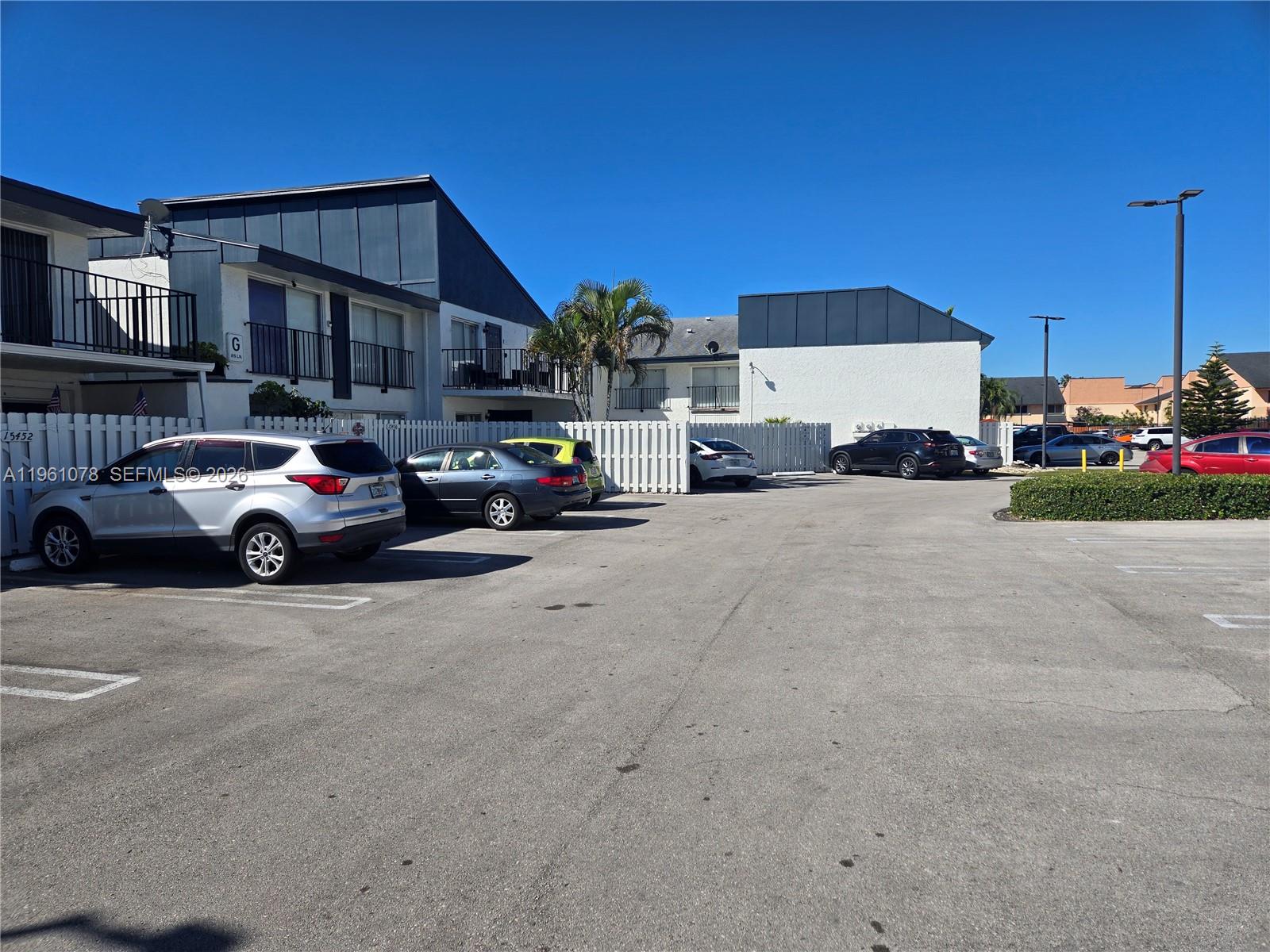 A parking lot sits in front of a two-story apartment building with white walls — 15454 SW 85th Ln # 135, Miami FL 33193, MIAMI, FL