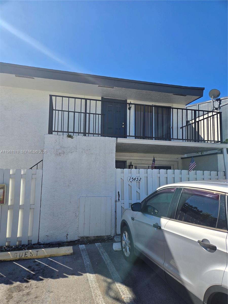 A two-story building exterior features a white fence, a balcony, and a parked car — 15454 SW 85th Ln # 135, Miami FL 33193, MIAMI, FL