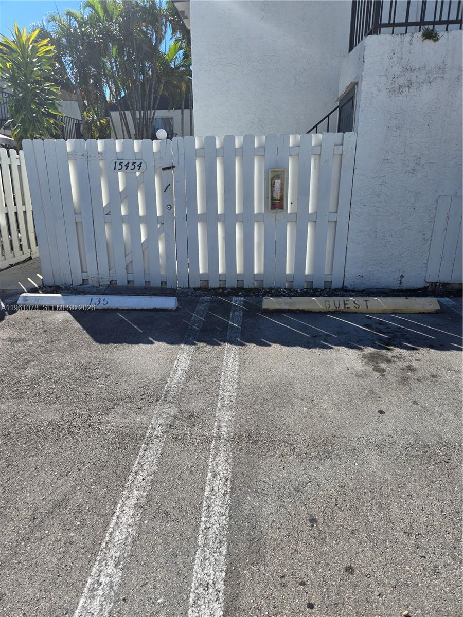 A white picket fence stands behind two parking spaces marked 135 and GUEST — 15454 SW 85th Ln # 135, Miami FL 33193, MIAMI, FL